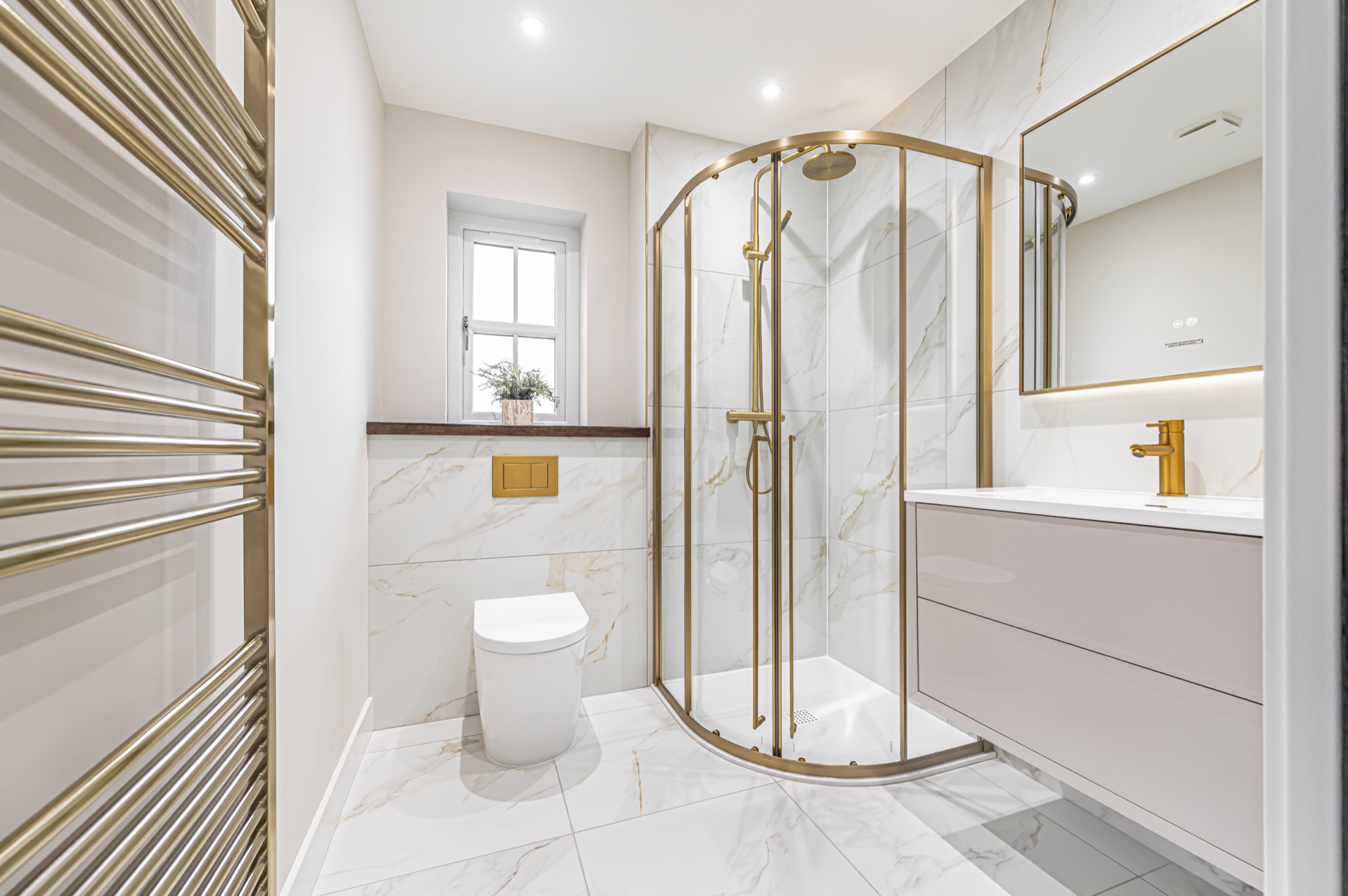 Ensuite bathroom with curved gold-framed shower enclosure and marble tiling