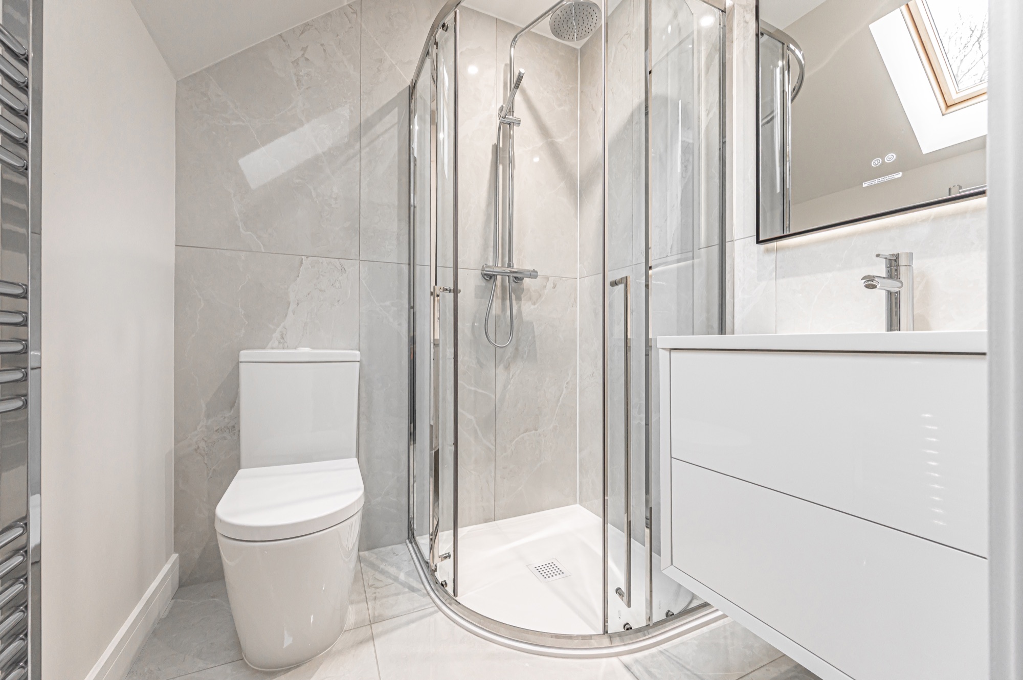Bathroom with grey marble tiling, chrome shower enclosure and skylight