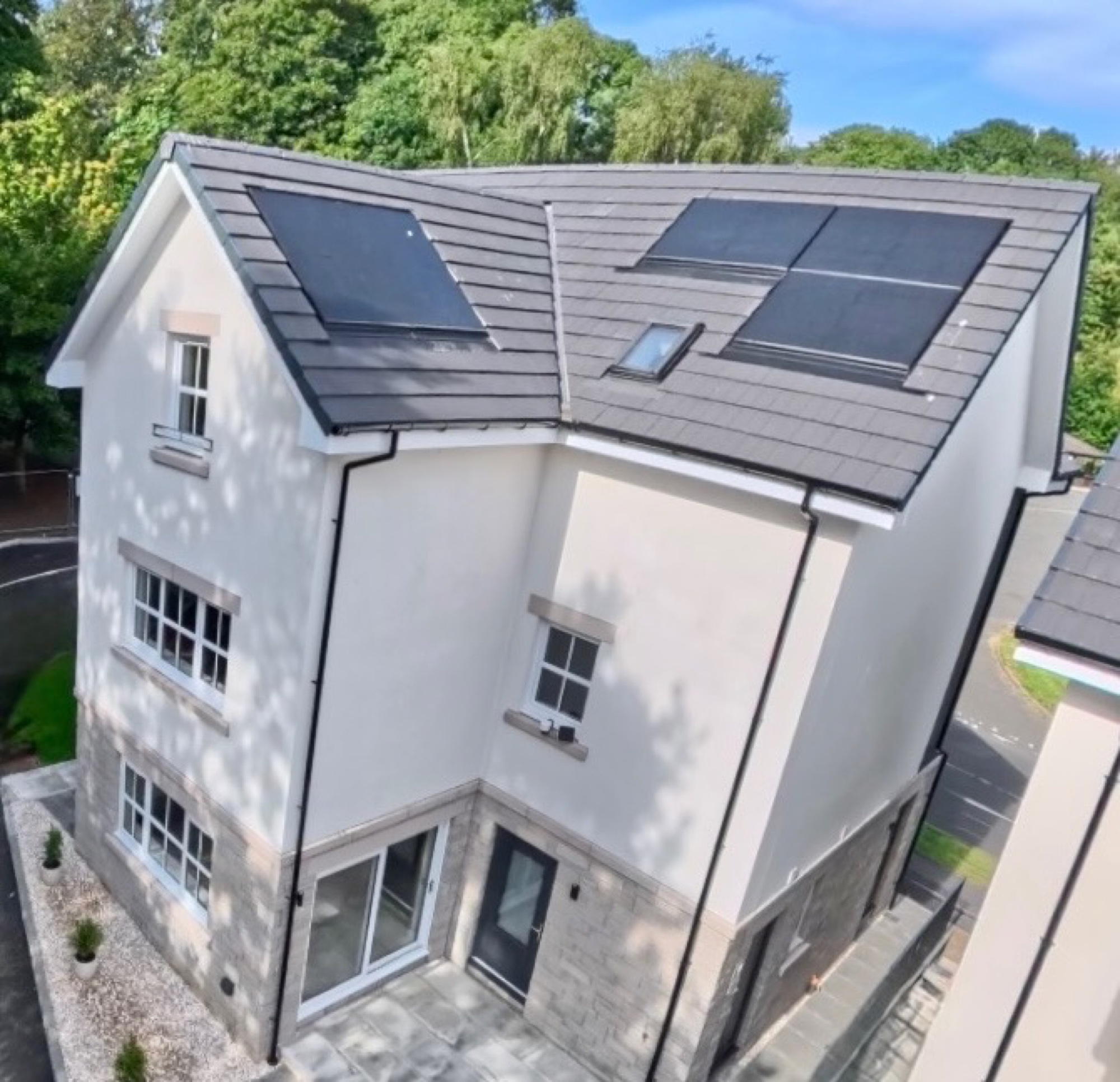 Close aerial view of a Braeview Gardens town home showing white render and natural stone exterior walls